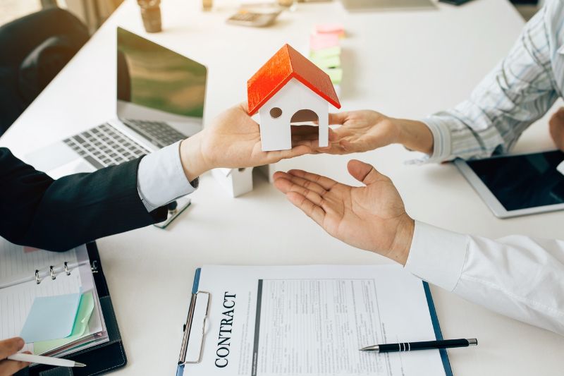 three hands lifting up a mini house model